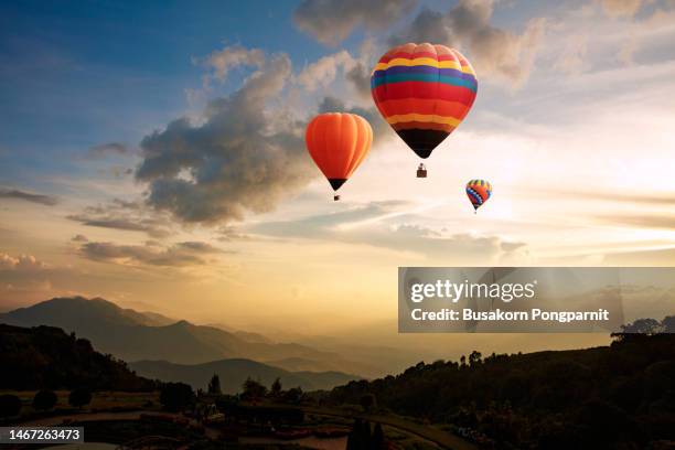 hot air balloon flying over landscape against sky during sunrise - heissluftballon stock-fotos und bilder