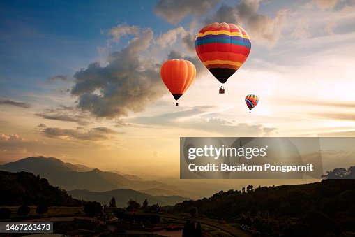 Hot Air Balloon Flying Over Landscape Against Sky During Sunrise