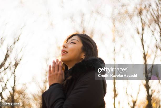 asian woman praying sincerely with both palms together - invocation stock pictures, royalty-free photos & images