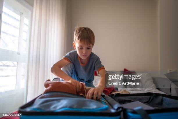 Boy packing or unpacking suitcase in a hotel room or at home preparing for travel