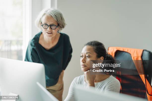 two businesswomen working together on computer at engineering office - new business construction stock pictures, royalty-free photos & images