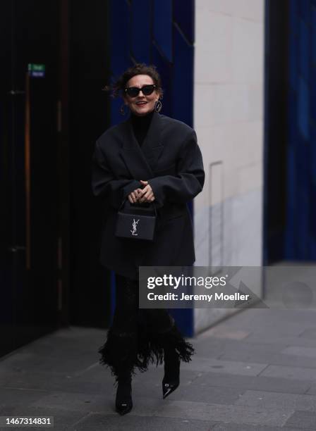 Renia Jaz seen wearing shades by Bottega Veneta, Chanel earrings, a bag by Yves Saint Laurent, a black transparent feather skirt, black high heels, a...