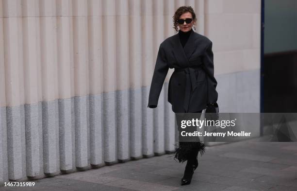 Renia Jaz seen wearing shades by Bottega Veneta, Chanel earrings, a bag by Yves Saint Laurent, a black transparent feather skirt, black high heels, a...