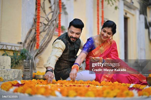 beautiful indian couple in traditional wear making floral rangoli together - hindu festival preparation stock-fotos und bilder