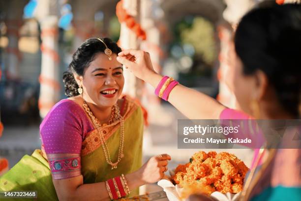 cheerful woman adjusting the bindi of another woman  in a marble pavilion of a palace - traditional festival bildbanksfoton och bilder