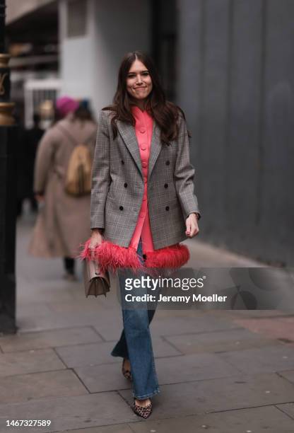 Fashion week guest seen wearing a patterned brown oversized blazer, a pink feather jacket, a brown bag, a long jeans and animal printed heels before...