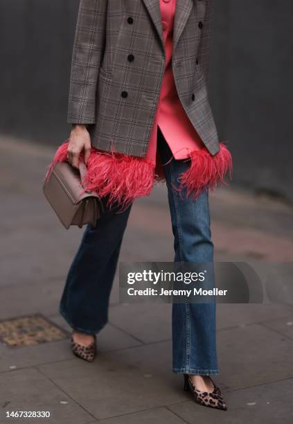 Fashion week guest seen wearing a patterned brown oversized blazer, a pink feather jacket, a brown bag, a long jeans and animal printed heels before...
