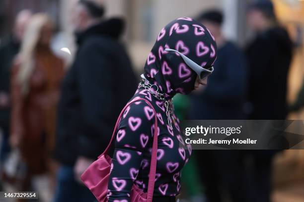 Fashion week guest seen wearing a hearted jumpsuit and matching hat, a pink bag and silver shades before the Mark Fast show during London Fashion...