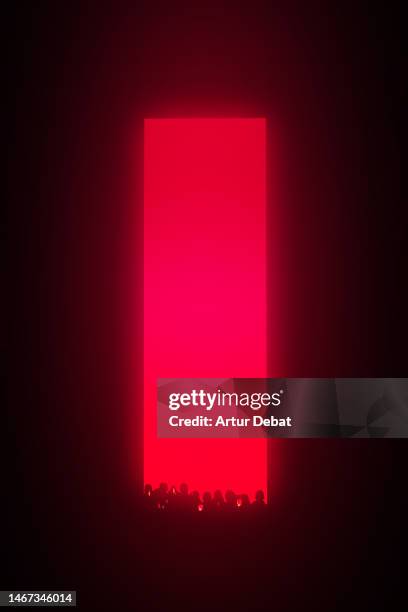 big red vertical rectangle neon illuminating at night with crowd of people. - magic doors stock-fotos und bilder