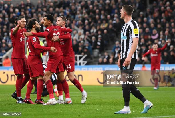 Cody Gakpo of Liverpool celebrates with teammates after scoring the team's second goal as Sven Botman of Newcastle United looks dejected during the...