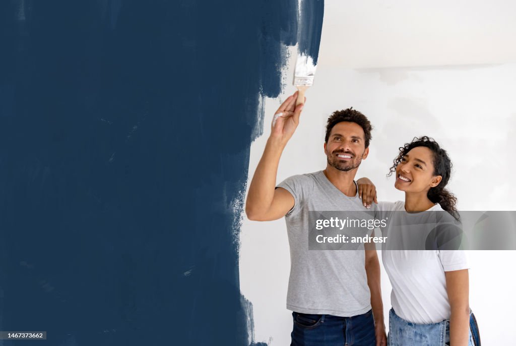 Happy couple painting their house