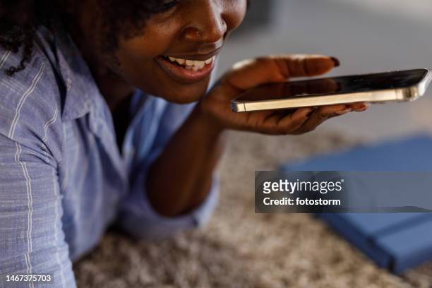 jeune femme allongée sur le sol, sur le devant, parlant au téléphone avec un ami - téléphone de téléconférence photos et images de collection