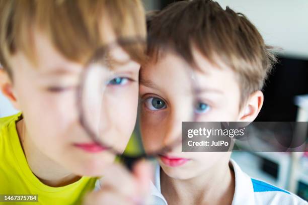 two boys looking at camera thought loupe - child magnifying glass stock pictures, royalty-free photos & images