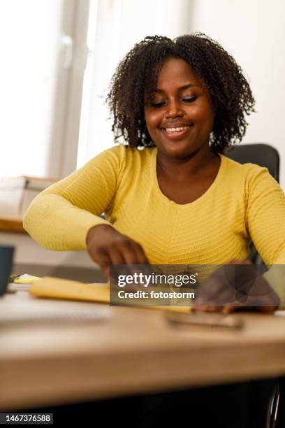 young businesswoman sealing a yellow envelope after packing a document inside - yellow envelope stock pictures, royalty-free photos & images