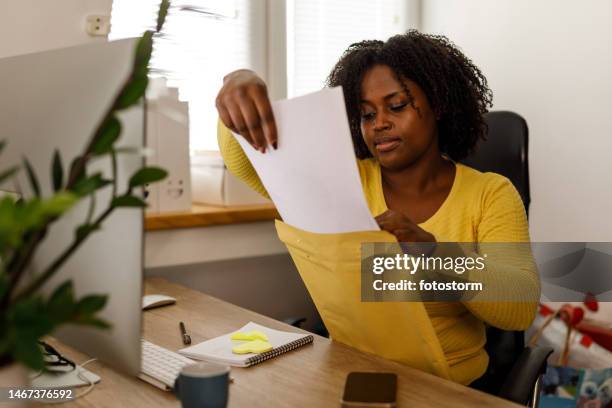 businesswoman packing documents from a yellow envelope - send stock pictures, royalty-free photos & images