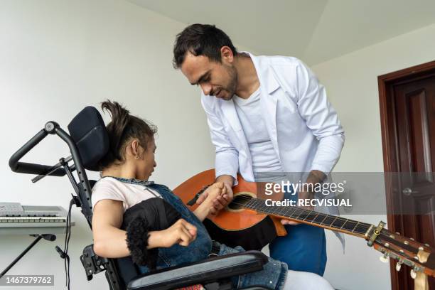 disabled girl in wheelchair performing music therapy treatment with the help of a music therapist at the comprehensive rehabilitation center for people with disabilities. - music therapy stock pictures, royalty-free photos & images