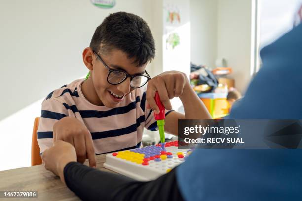 fisioterapeuta que realiza terapia motora fina a un niño discapacitado en el centro de salud para niños discapacitados. realización de actividades de rehabilitación integral para discapacitados. - terapia ocupacional fotografías e imágenes de stock