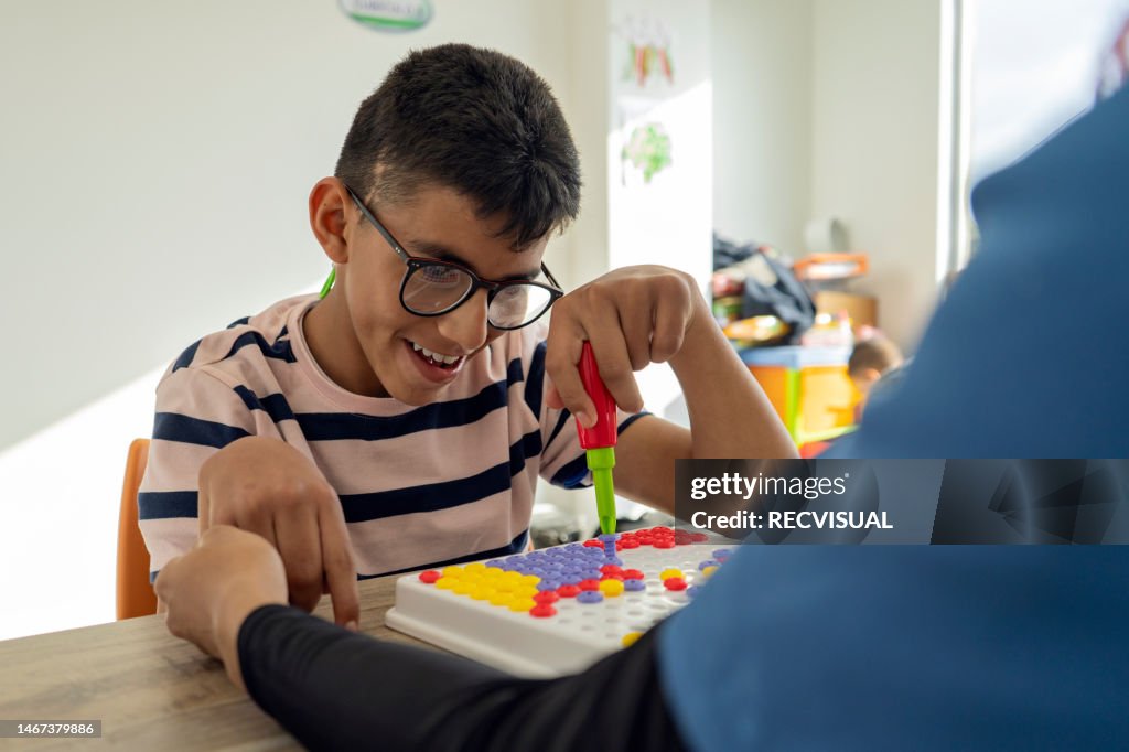 Physiotherapist performing fine motor therapy to a disabled child at the health center for disabled children. performing comprehensive rehabilitation activities for the disabled.