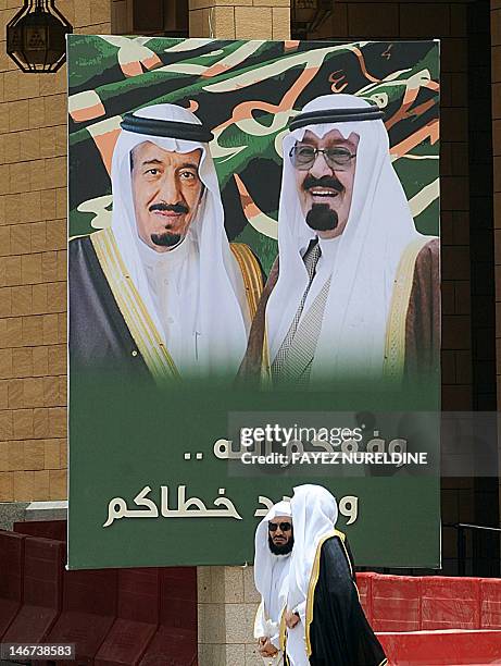Saudi men walk past a poster of newly appointed Crown Prince Salman bin Abdulaziz and his brother King Abdullah outside the Masmak Palace in Riyadh,...