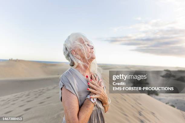 active and happy senior woman dancing in sand dunes - senior spirituality stock pictures, royalty-free photos & images