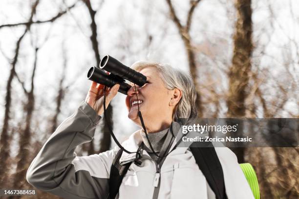 mature senior hiker looking through binoculars - bird watching stock pictures, royalty-free photos & images