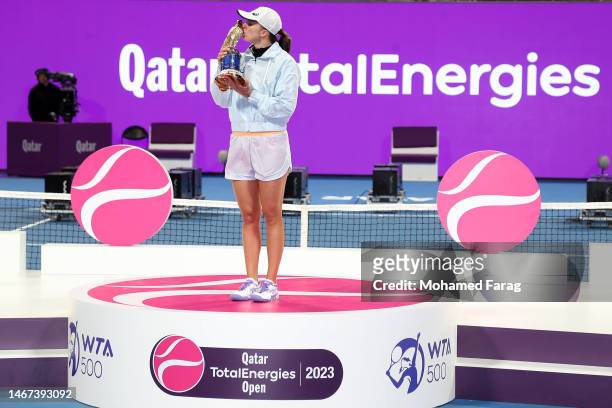 Iga Swiatek of Poland celebrates with the trophy on the podium after defeating Jessica Pegula of USA in the final match on day six of the Qatar Total...