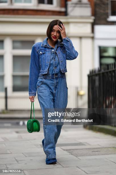 Tiffany Hsu wears a blue denim jumpsuit, a blue denim jacket, a green bag, outside 16Arlington, during London Fashion Week February 2023 on February...