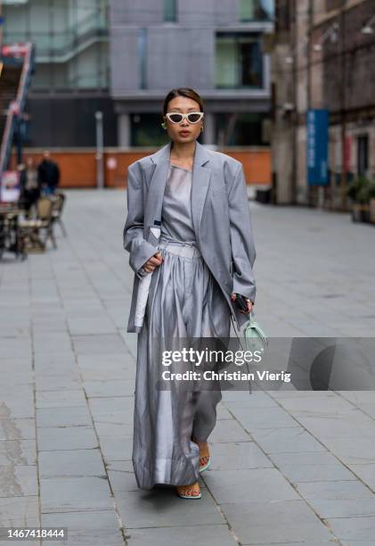 Rosana Lai wearing grey oversized blazer, high waisted pants, mint green bag, top sandals, white sunglasses outside Eudon Choi during London Fashion...