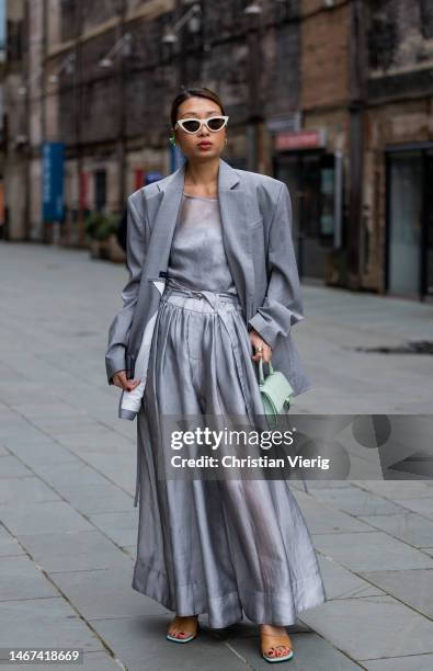 Rosana Lai wearing grey oversized blazer, high waisted pants, mint green bag, top sandals, white sunglasses outside Eudon Choi during London Fashion...