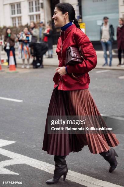 Caroline Issa wearing a long brown pleated skirt, red jacket, and burgundy red bag outside Roksanda during London Fashion Week February 2023 on...