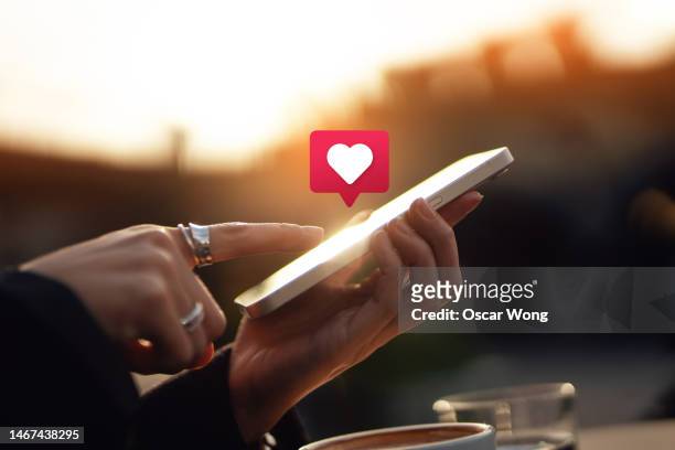 connecting with social media network via smartphone - aplicación para móviles fotografías e imágenes de stock