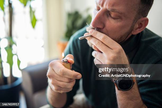 man lighting up a marijuana joint. - smoking joint stock pictures, royalty-free photos & images
