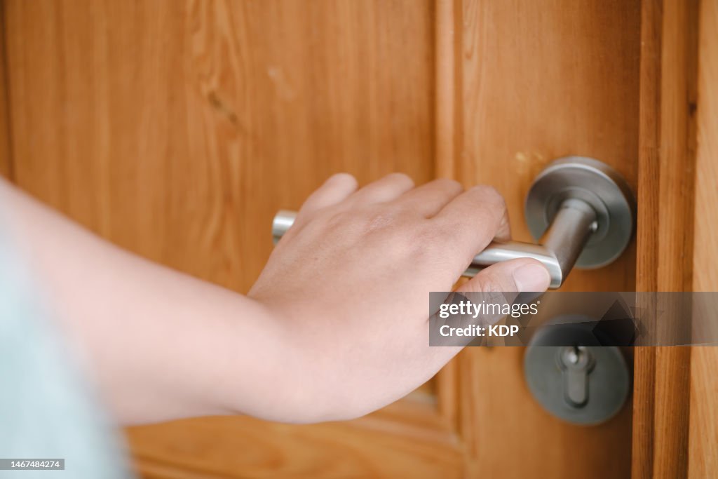 Close-Up of Woman Hand is Holding Handle Door to Opening a Door Access in Apartment