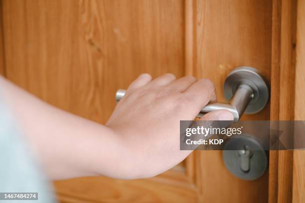 close-up of woman hand is holding handle door to opening a door access in apartment - door knob stock pictures, royalty-free photos & images