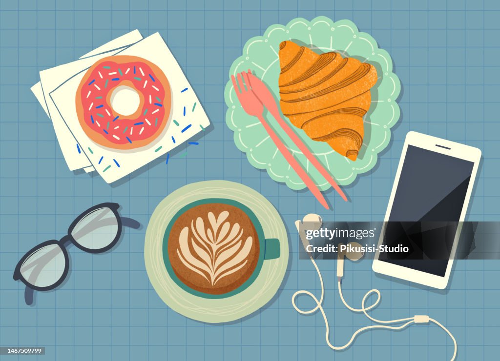 Top view breakfast table with croissant, donut, coffee and smartphone.