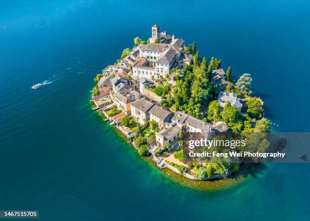 a small ferry leaving isola san giulio (st. julius island) in lake orta, italy - piedmont italy stock pictures, royalty-free photos & images