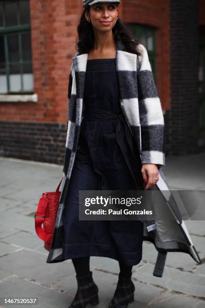 Guest is seen wearing a monochrome wool coat with a denim Dress and red leather bag outside the Eudon Choi show during London Fashion Week February...