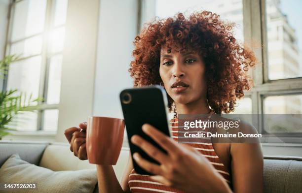 black woman, coffee cup and reading on sofa with phone for social media, chat app or web in living room. african gen z girl, smartphone ui and texting for networking, email or article on news website - z com stock pictures, royalty-free photos & images