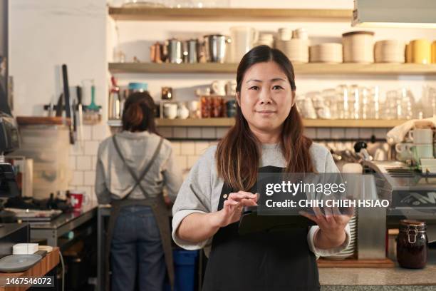 photo of asia cafe owner in coffee shop smiling and hold a wireless digital tablet. - waitress stock pictures, royalty-free photos & images