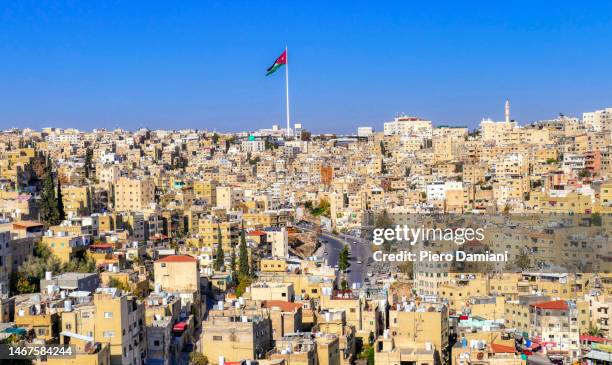 december 18, 2022. amman - jordan. panoramic view of amman on a clear winter day with jordanian flag on a pole in the background. - amman stock pictures, royalty-free photos & images