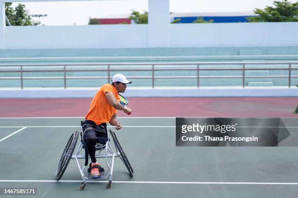 man in wheelchair playing tennis outdoors - wheelchair tennis stock pictures, royalty-free photos & images