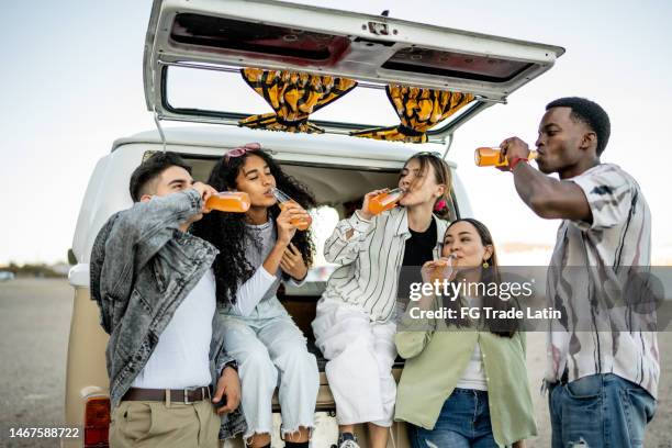 group of young friends drinking soda on the trunk of a van outdoors - drinking soda in car stock pictures, royalty-free photos & images