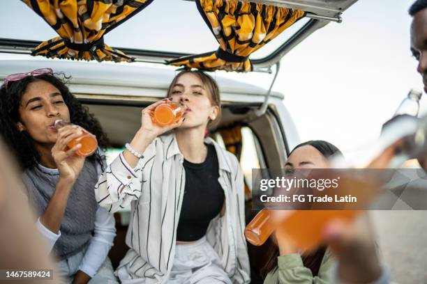 group of young friends drinking soda on the trunk of a van outdoors - drinking soda in car stock pictures, royalty-free photos & images