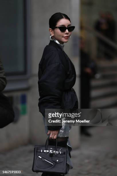 Tia Lee seen wearing black shades, a silver dress, a black bomber jacket and a black Hermes Birkin bag before the DAVID KOMA show during London...