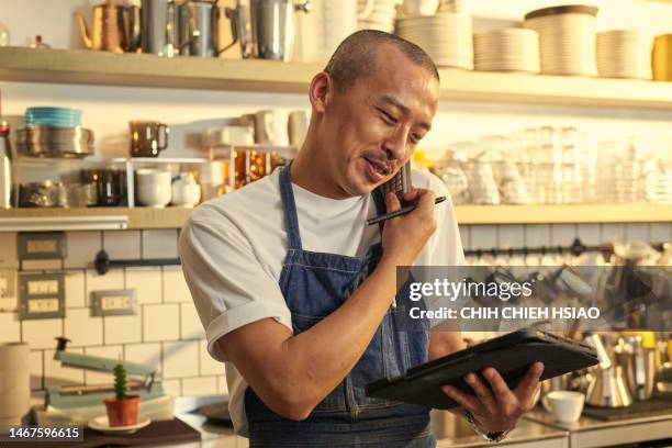 photo of asia cafe owner in coffee shop answer a call and hold a wireless digital tablet order products online. - chinese waiter stock pictures, royalty-free photos & images