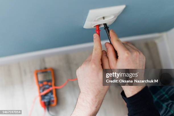 man measures the current in outlet - multimeter stock pictures, royalty-free photos & images