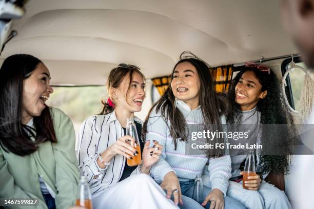 girlfriends talking while drinking soda on retro mini van transport - drinking soda in car stock pictures, royalty-free photos & images