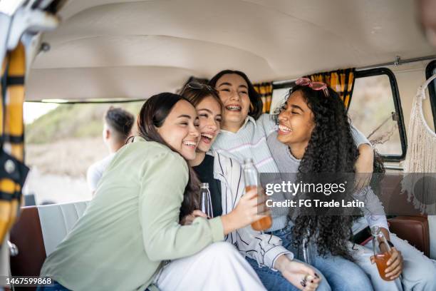 girlfriends embracing while drinking soda on retro mini van transport - drinking soda in car stock pictures, royalty-free photos & images