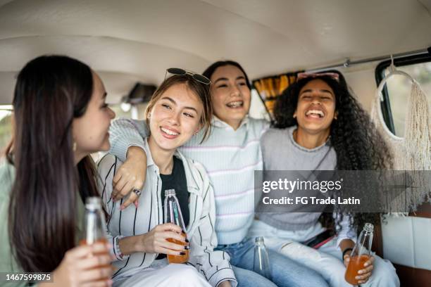 girlfriends embracing while drinking soda on retro mini van transport - drinking soda in car stock pictures, royalty-free photos & images