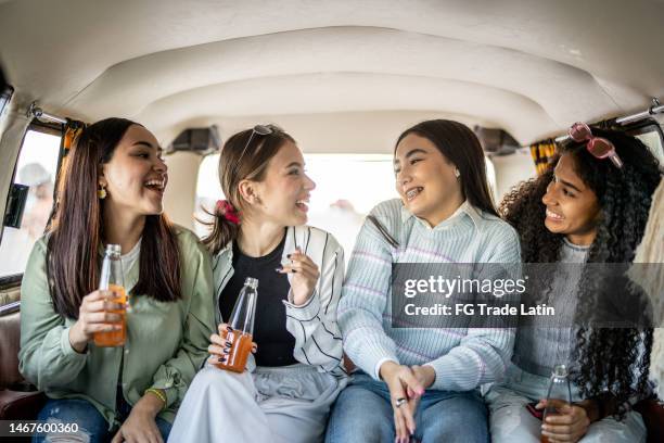 girlfriends talking while drinking soda on retro mini van transport - drinking soda in car stock pictures, royalty-free photos & images